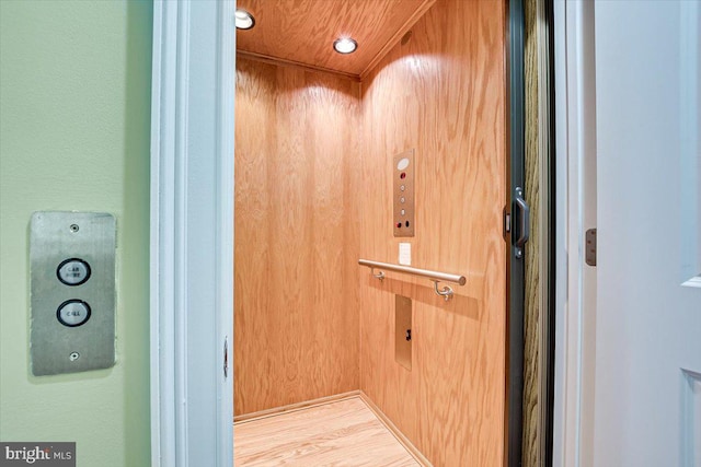 room details featuring wood-type flooring, wood walls, and elevator