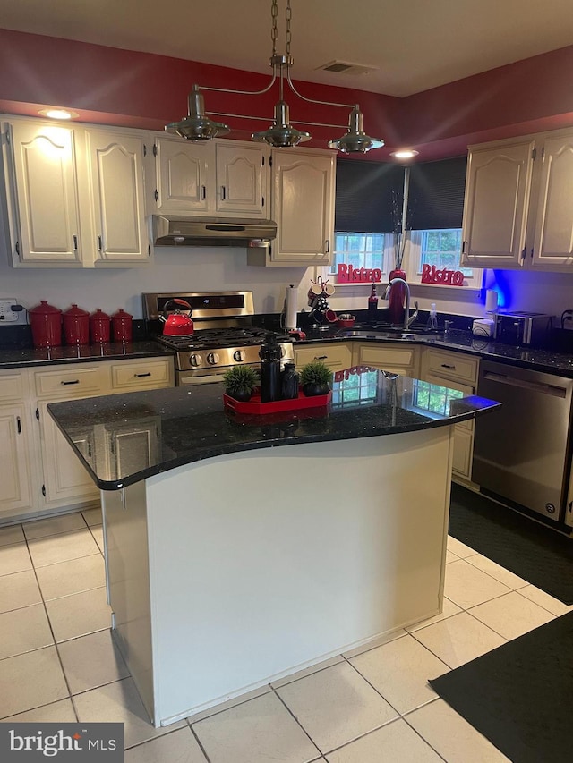 kitchen featuring exhaust hood, dark stone countertops, a center island, light tile patterned floors, and appliances with stainless steel finishes