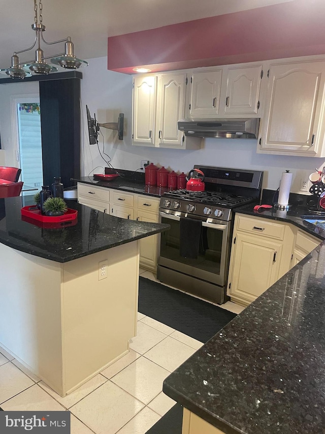 kitchen with white cabinets, dark stone countertops, gas stove, and light tile patterned floors