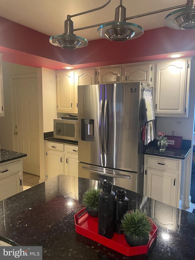 kitchen featuring white cabinets, stainless steel appliances, light tile patterned floors, and dark stone counters