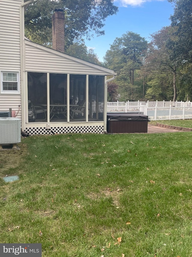 view of yard featuring a hot tub, central AC, and a sunroom