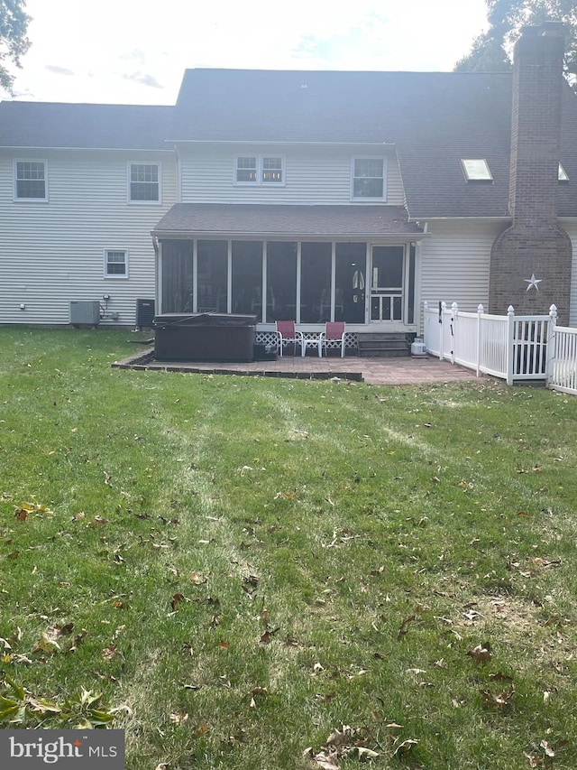 back of house featuring central air condition unit, a yard, a patio, and a sunroom