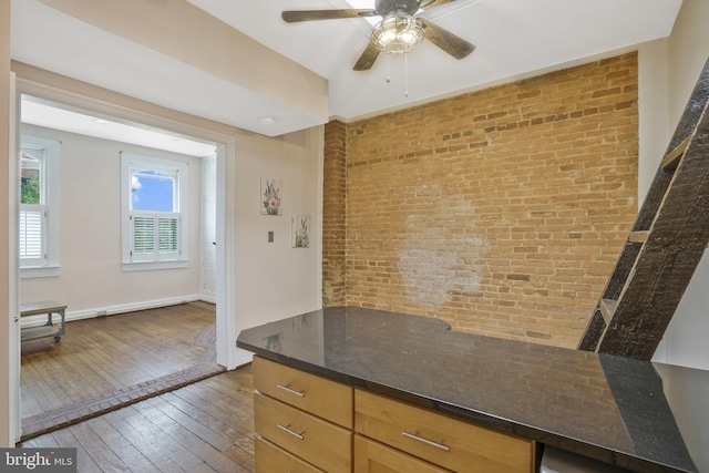 kitchen with ceiling fan, brick wall, and dark hardwood / wood-style flooring