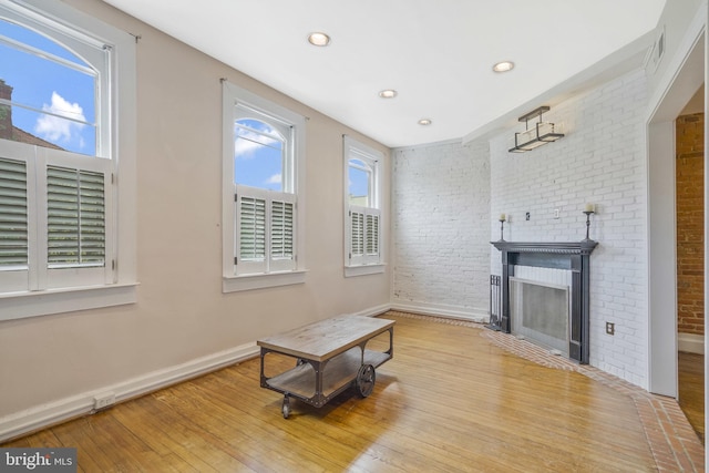 living area with light hardwood / wood-style floors, brick wall, and a fireplace