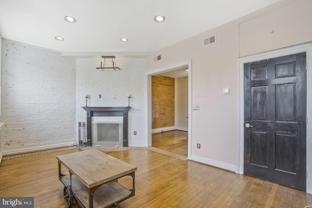 living room featuring wood-type flooring and brick wall