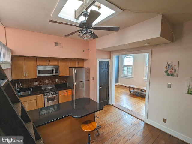 kitchen featuring appliances with stainless steel finishes, tasteful backsplash, wood-type flooring, ceiling fan, and sink