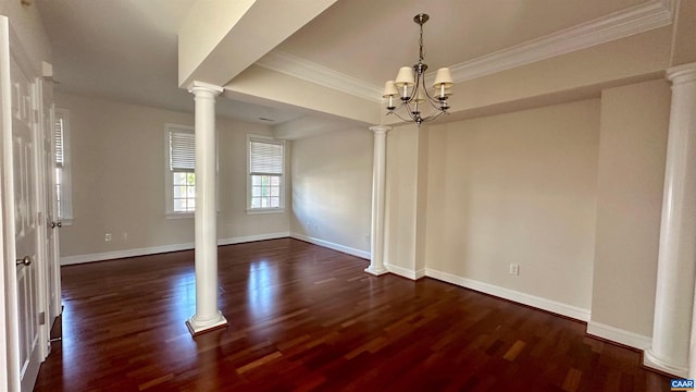 spare room featuring ornamental molding, a chandelier, decorative columns, and dark wood-type flooring