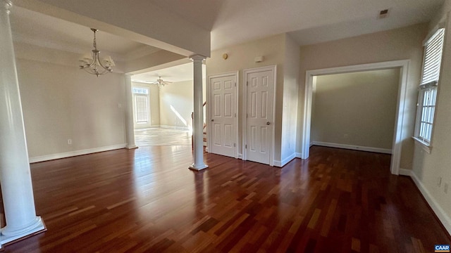 interior space featuring an inviting chandelier, two closets, dark hardwood / wood-style floors, and decorative columns