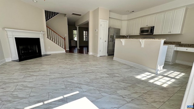 kitchen featuring dark stone counters, white cabinetry, a breakfast bar area, and stainless steel appliances