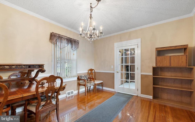 dining space with ornamental molding, a textured ceiling, a chandelier, and hardwood / wood-style floors