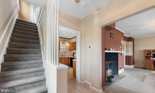 stairs with ornamental molding, sink, a textured ceiling, tile patterned floors, and a fireplace