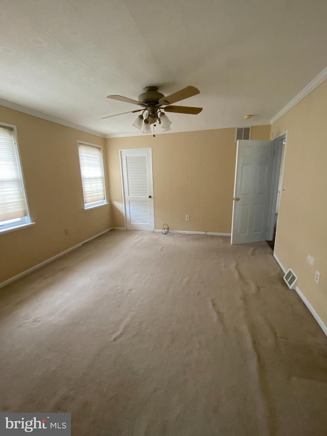 interior space featuring carpet floors, ornamental molding, and ceiling fan