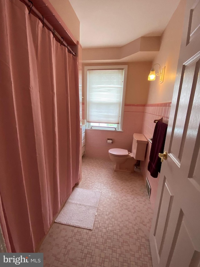 bathroom with tile walls, toilet, and a shower with shower curtain