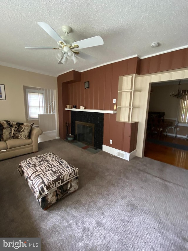 carpeted living room featuring ceiling fan, a textured ceiling, a fireplace, and ornamental molding