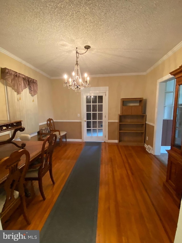 dining room featuring a textured ceiling, wood-type flooring, ornamental molding, and a notable chandelier