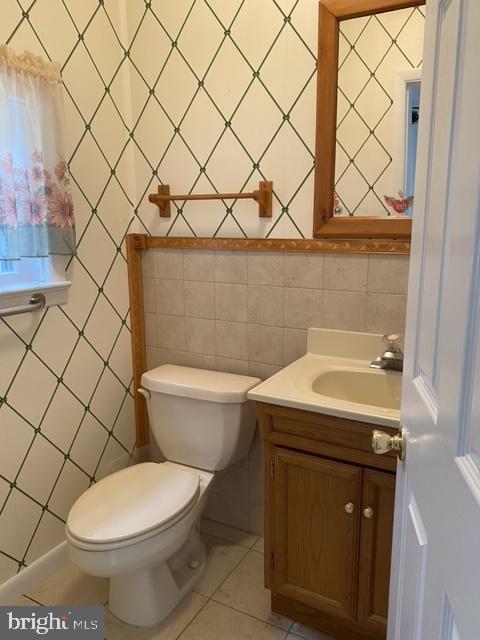 bathroom with vanity, tile walls, tile patterned flooring, and toilet