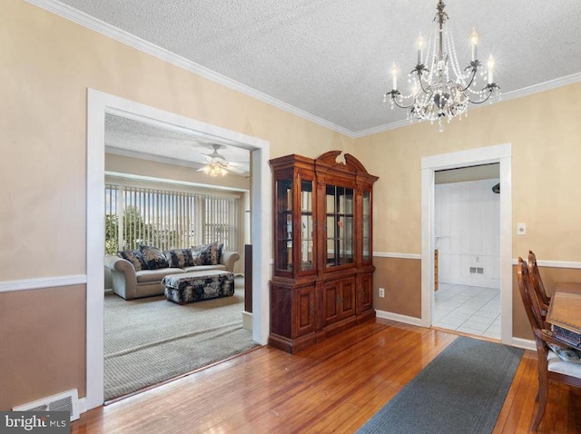 dining space featuring ceiling fan with notable chandelier, a textured ceiling, and light wood-type flooring