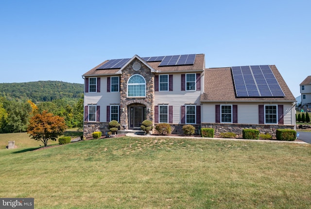 colonial-style house with a front yard, a mountain view, and solar panels