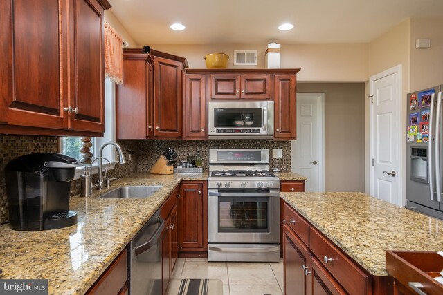 kitchen with appliances with stainless steel finishes, light stone countertops, decorative backsplash, and sink