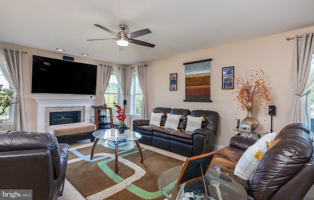 living room featuring carpet, a tiled fireplace, and ceiling fan