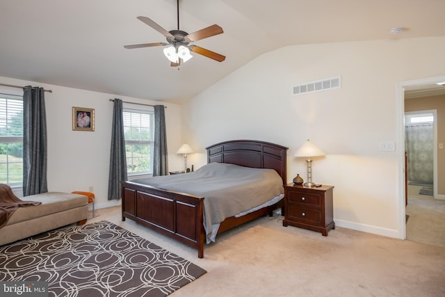 bedroom with light carpet, vaulted ceiling, ceiling fan, and ensuite bath