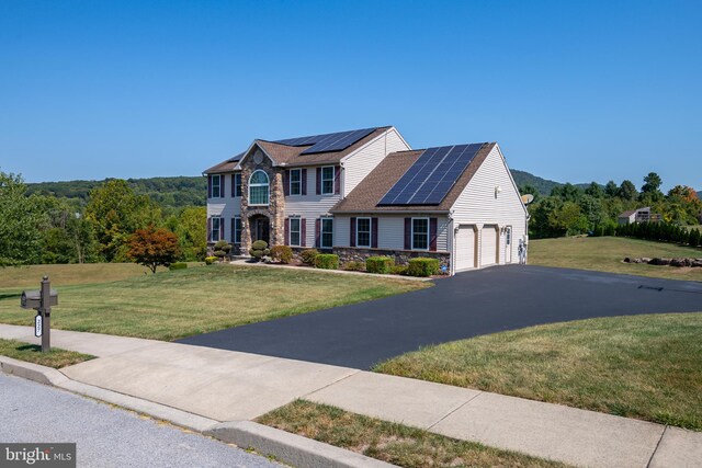 view of front of home with solar panels and a front yard