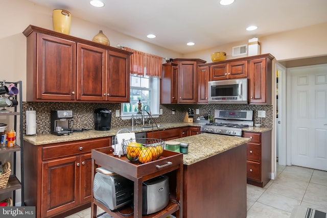 kitchen featuring light stone counters, tasteful backsplash, light tile patterned floors, stainless steel appliances, and sink