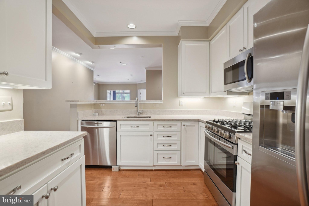 kitchen featuring white cabinets, sink, light stone countertops, light wood-type flooring, and stainless steel appliances