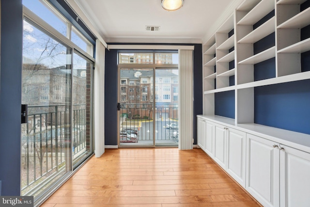 doorway featuring light hardwood / wood-style flooring, a wealth of natural light, and ornamental molding