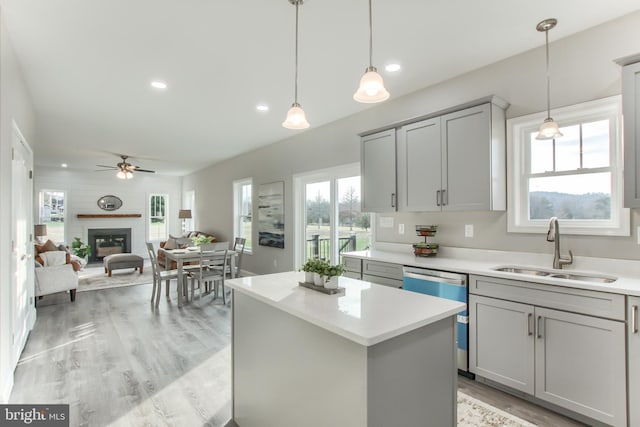 kitchen with pendant lighting, dishwasher, sink, gray cabinetry, and a large fireplace