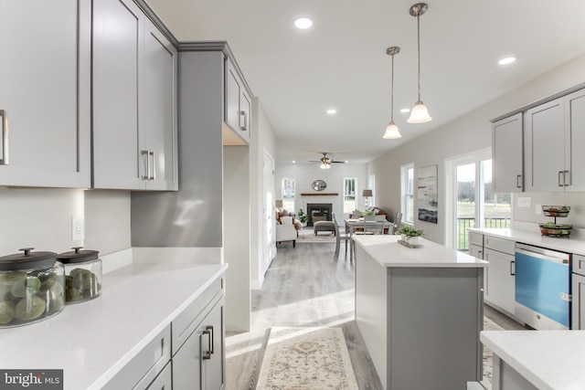 kitchen featuring gray cabinetry, decorative light fixtures, light hardwood / wood-style flooring, and stainless steel dishwasher