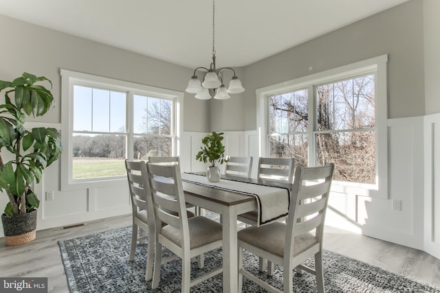 dining room with light hardwood / wood-style flooring, a wealth of natural light, and a chandelier