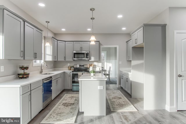 kitchen featuring pendant lighting, gray cabinets, sink, a kitchen island, and stainless steel appliances