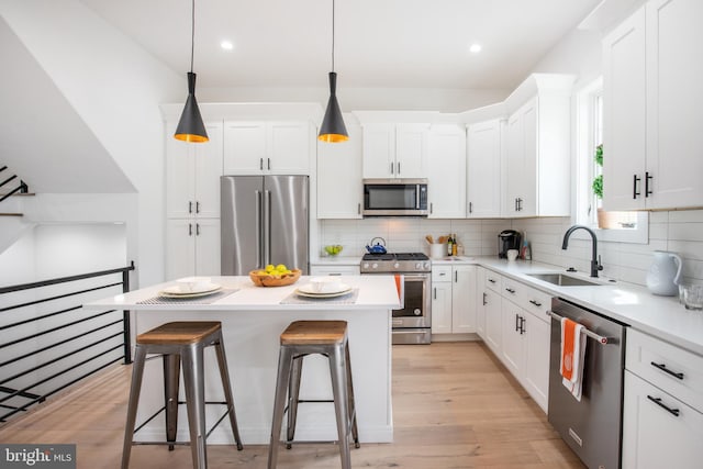 kitchen featuring stainless steel appliances, white cabinets, a center island, and sink