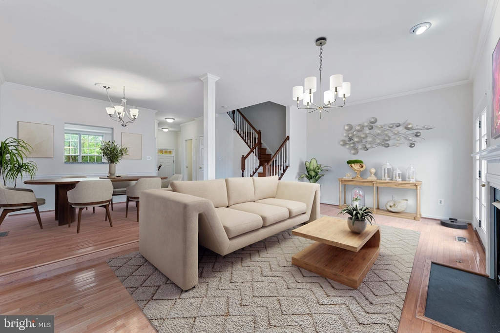 living room featuring an inviting chandelier, light hardwood / wood-style floors, and crown molding