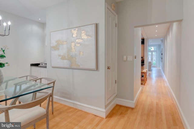 corridor with an inviting chandelier and light wood-type flooring