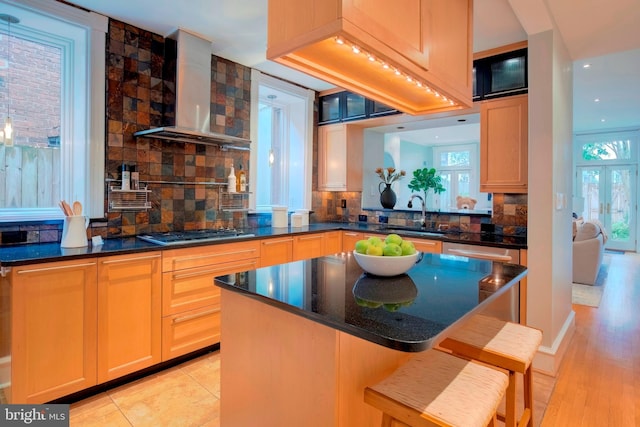 kitchen with light wood-type flooring, sink, stainless steel gas cooktop, wall chimney exhaust hood, and backsplash