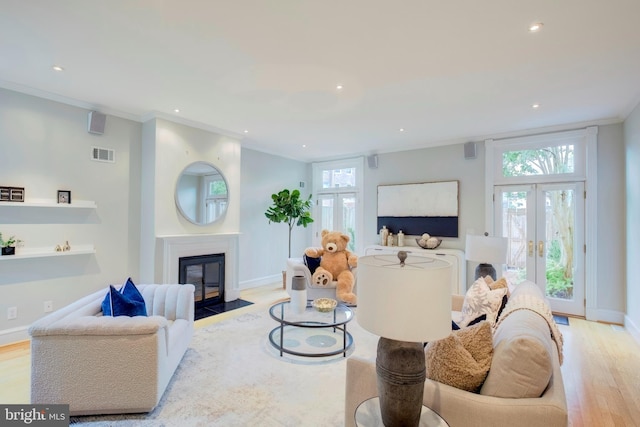 living room with light wood-type flooring, ornamental molding, and french doors