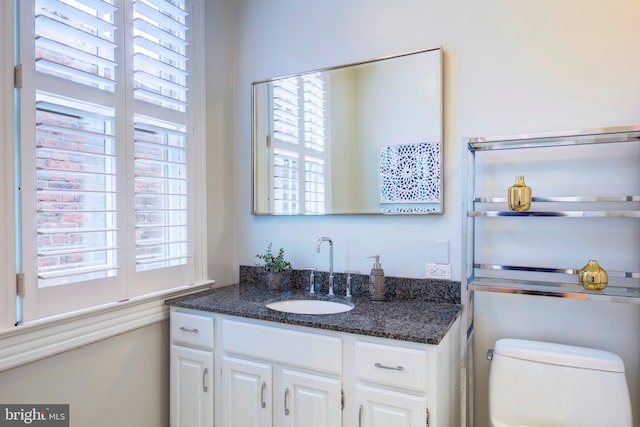 bathroom featuring a healthy amount of sunlight, vanity, and toilet