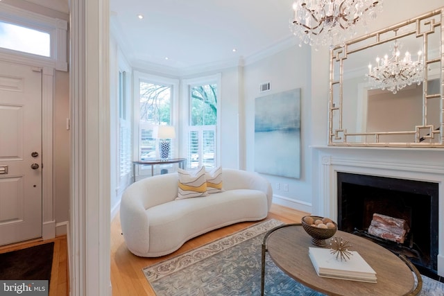 living area with ornamental molding, an inviting chandelier, and hardwood / wood-style floors