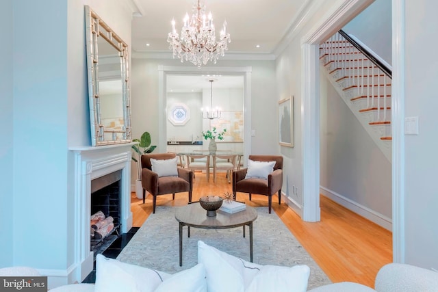 living area featuring a notable chandelier, wood-type flooring, and crown molding