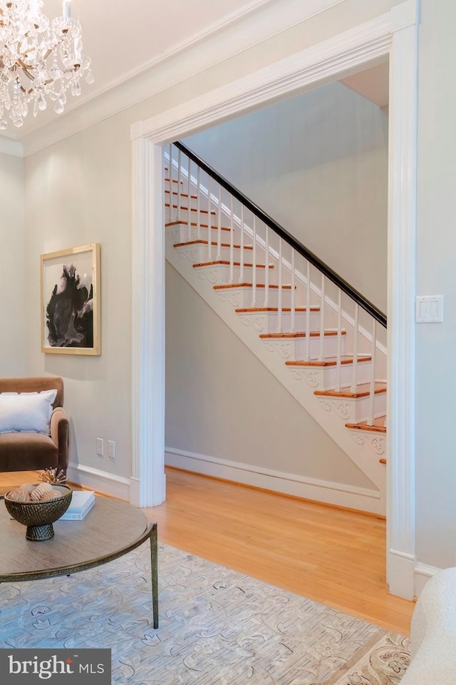 stairway featuring wood-type flooring, crown molding, and an inviting chandelier