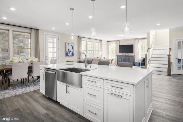 kitchen featuring a kitchen island with sink, hanging light fixtures, sink, and white cabinetry