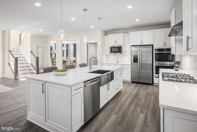 kitchen featuring pendant lighting, white cabinets, a center island with sink, and appliances with stainless steel finishes