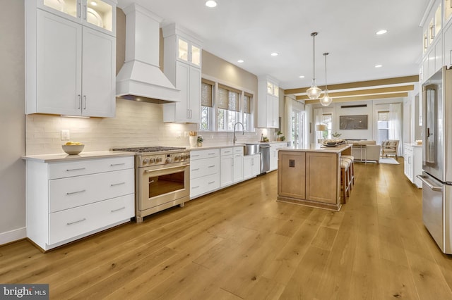 kitchen featuring white cabinetry, a center island, custom exhaust hood, and premium appliances