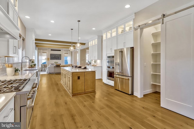 kitchen featuring decorative light fixtures, white cabinets, a center island, stainless steel appliances, and a barn door