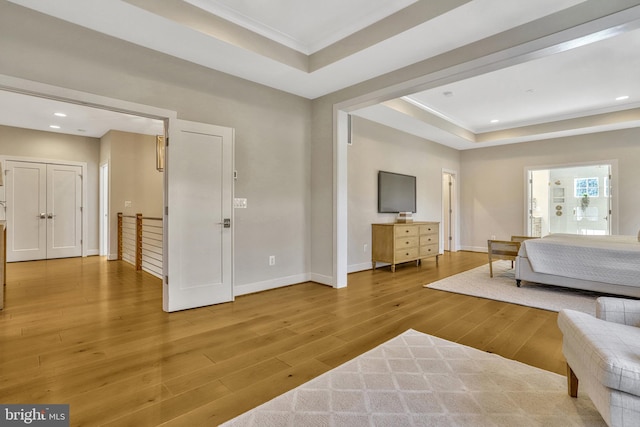 bedroom with a raised ceiling, ornamental molding, and hardwood / wood-style floors