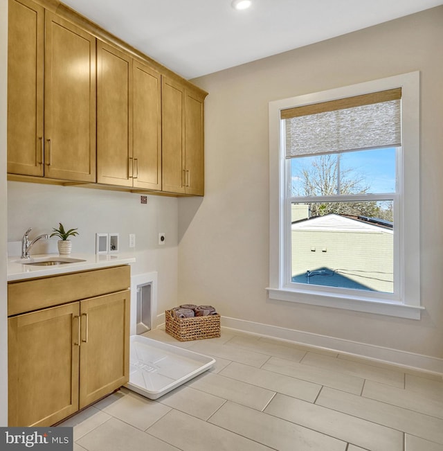 laundry area with cabinets, electric dryer hookup, sink, and light tile patterned floors