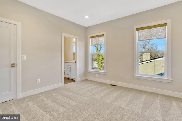 unfurnished bedroom featuring light carpet and ensuite bath