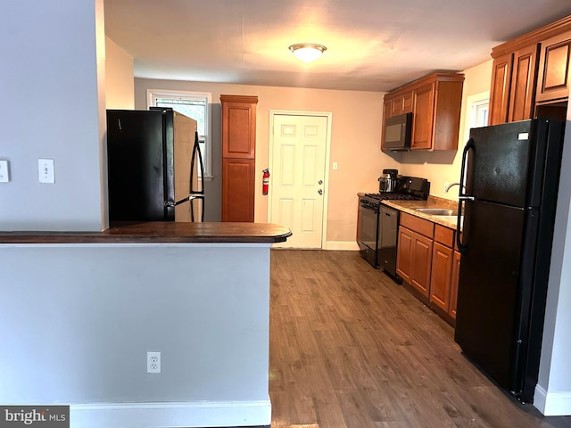 kitchen with black appliances, dark hardwood / wood-style floors, and sink